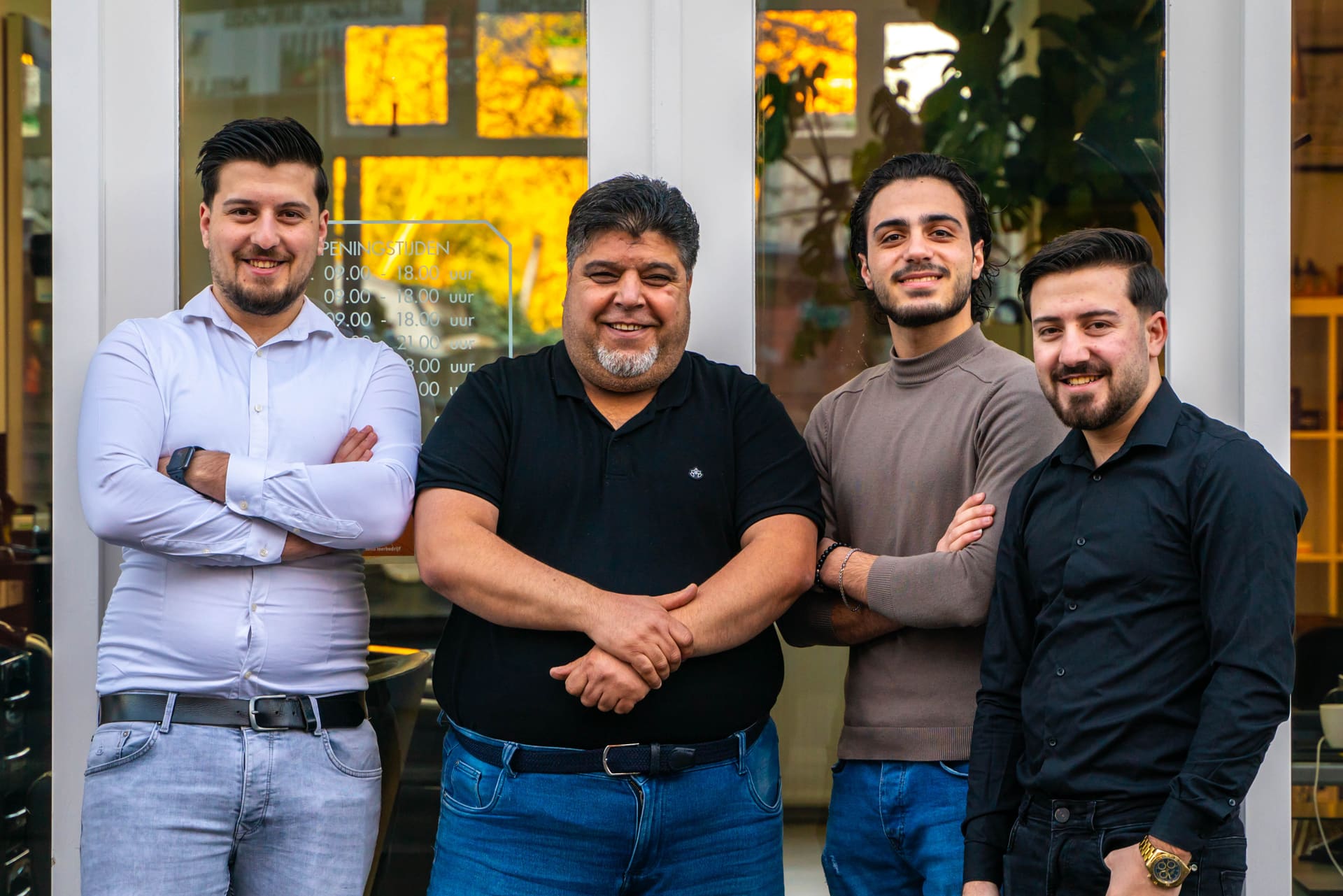 De vier kappers van Kapsalon Assendorp samen voor de etalage van de salon.